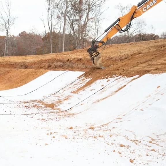 Geosynthetic clay liner being covered with its protective soil layer on site