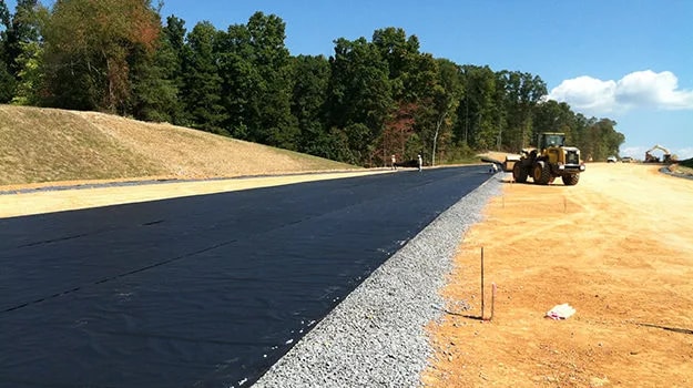 Separation geotextile deployed beneath a road embankment